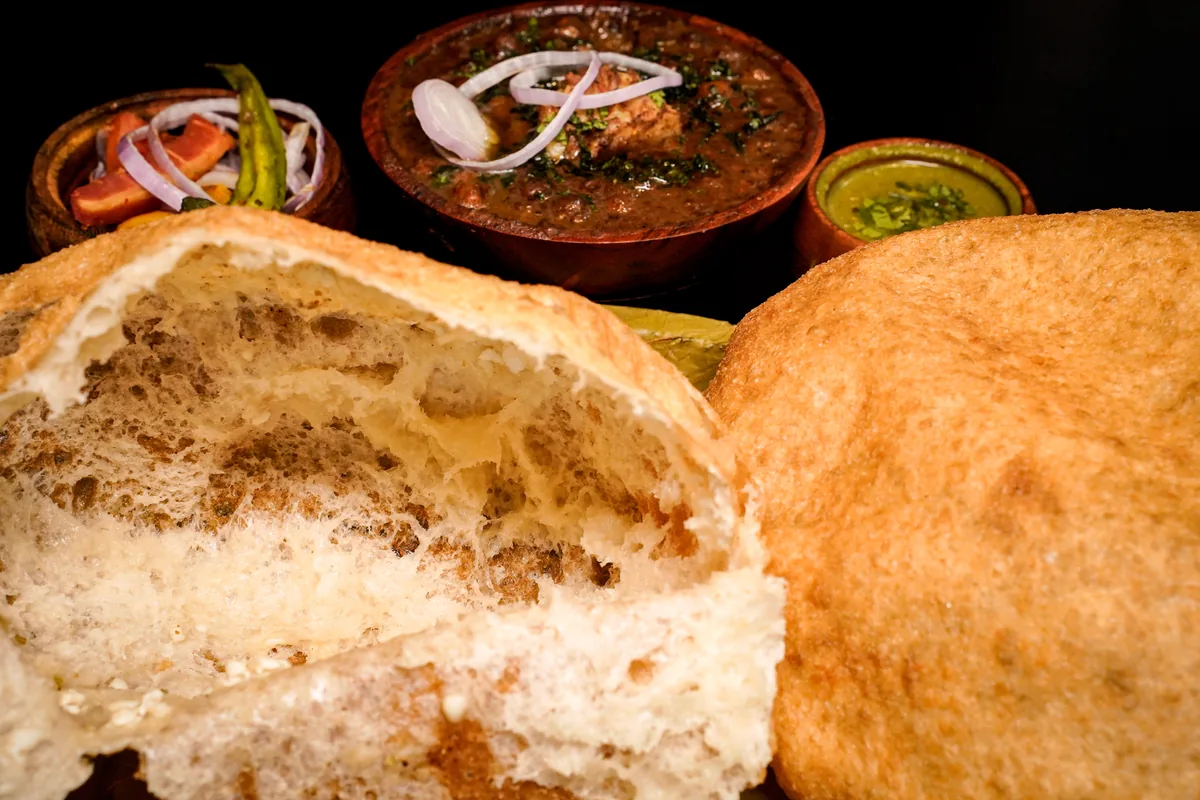 A bhatura torn open, soft and airy