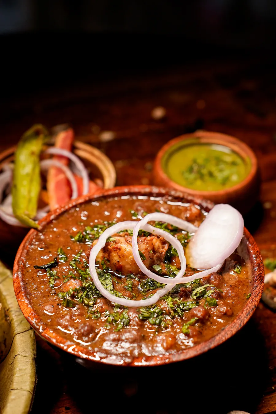 Chole in a wooden bowl with onion rings and mint