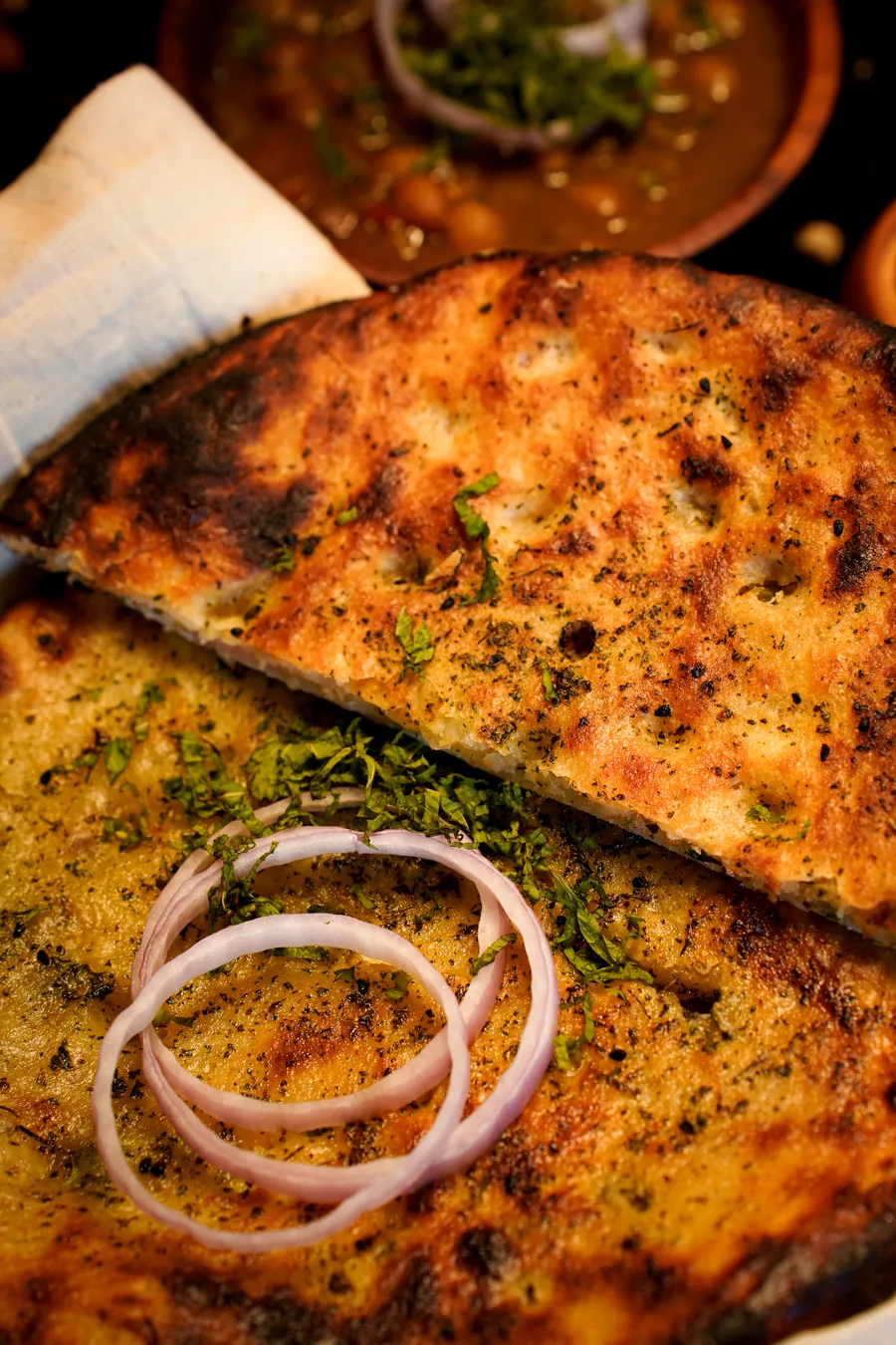 Close-up of a charred, mint-flecked kulcha